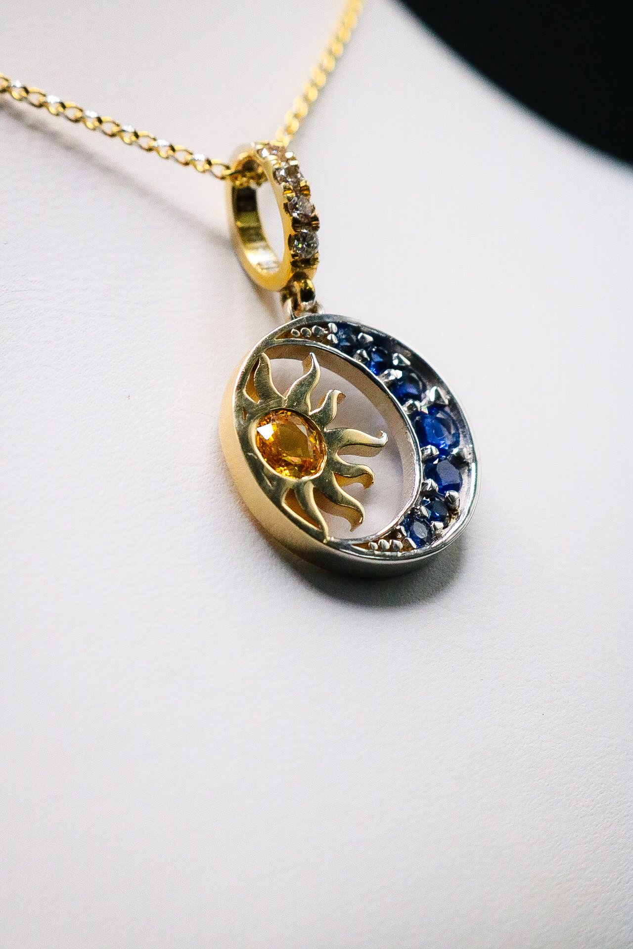 Close view of sun and moon pendant showing yellow sapphire sun and blue sapphire crescent